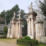 Ornate baroque gate with statues in Lamego, Portugal, surrounded by lush greenery.