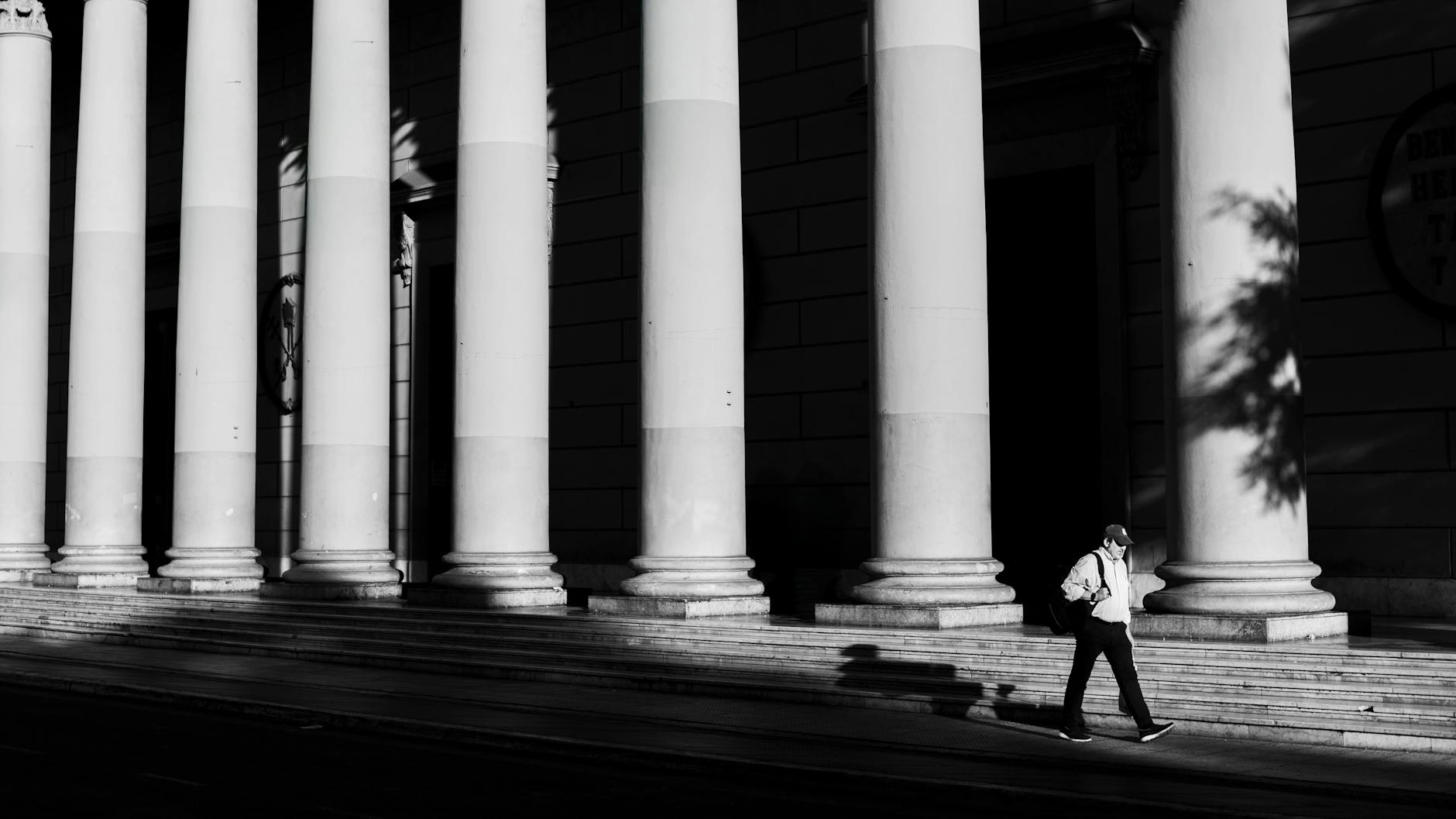 A solitary figure walks past grand columns in Buenos Aires, Argentina.