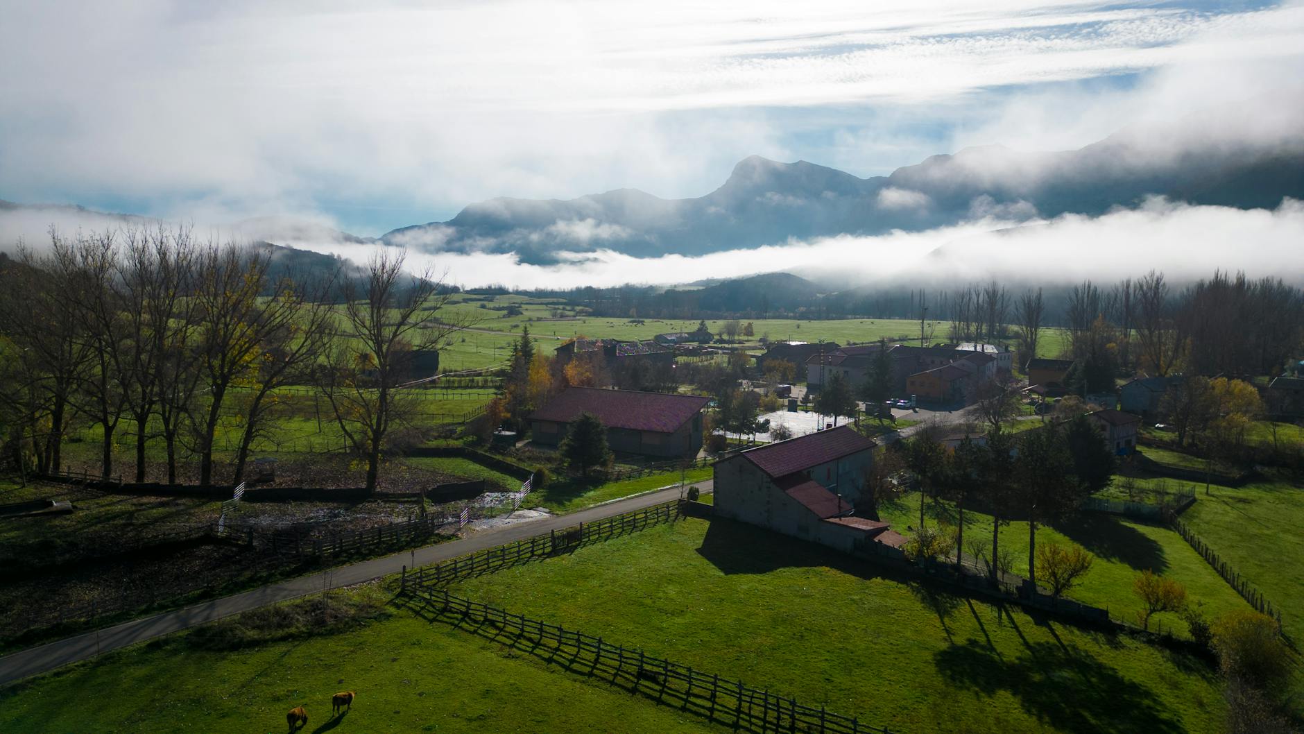 Scenic view of a misty rural landscape in Riaño, Spain with mountains and farms.
