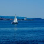 A tranquil scene of a sailboat gliding across the blue waters of Vigo Bay, Spain.