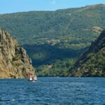 A boat navigates between steep cliffs in the scenic Ribeira Sacra, Galicia, Spain, showcasing stunning natural beauty.