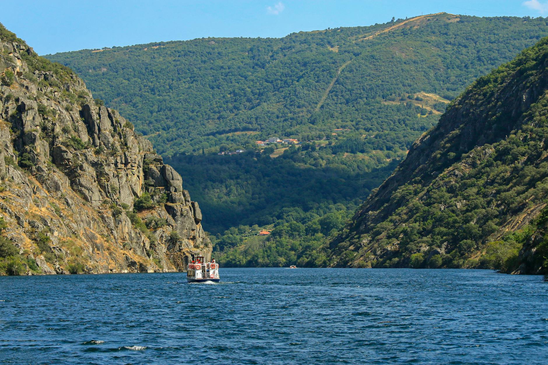 A boat navigates between steep cliffs in the scenic Ribeira Sacra, Galicia, Spain, showcasing stunning natural beauty.