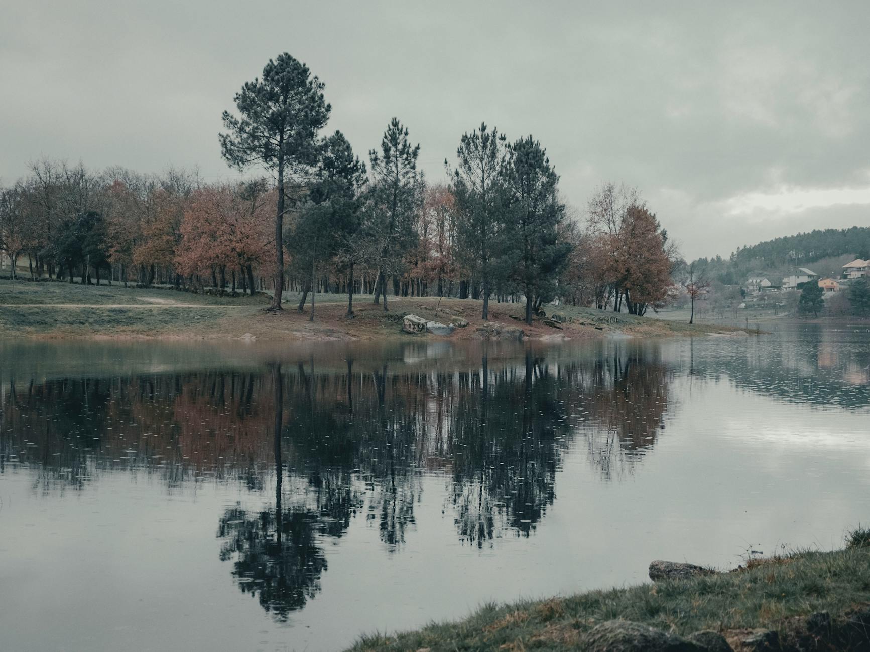 Tranquil autumn landscape with trees reflected in a lake at Cachamuíña, Galicia, Spain.