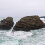 Ocean cliffs with waves crashing against rocks near a rugged coastline.