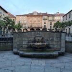 Charming old European square with a central fountain and historic buildings.