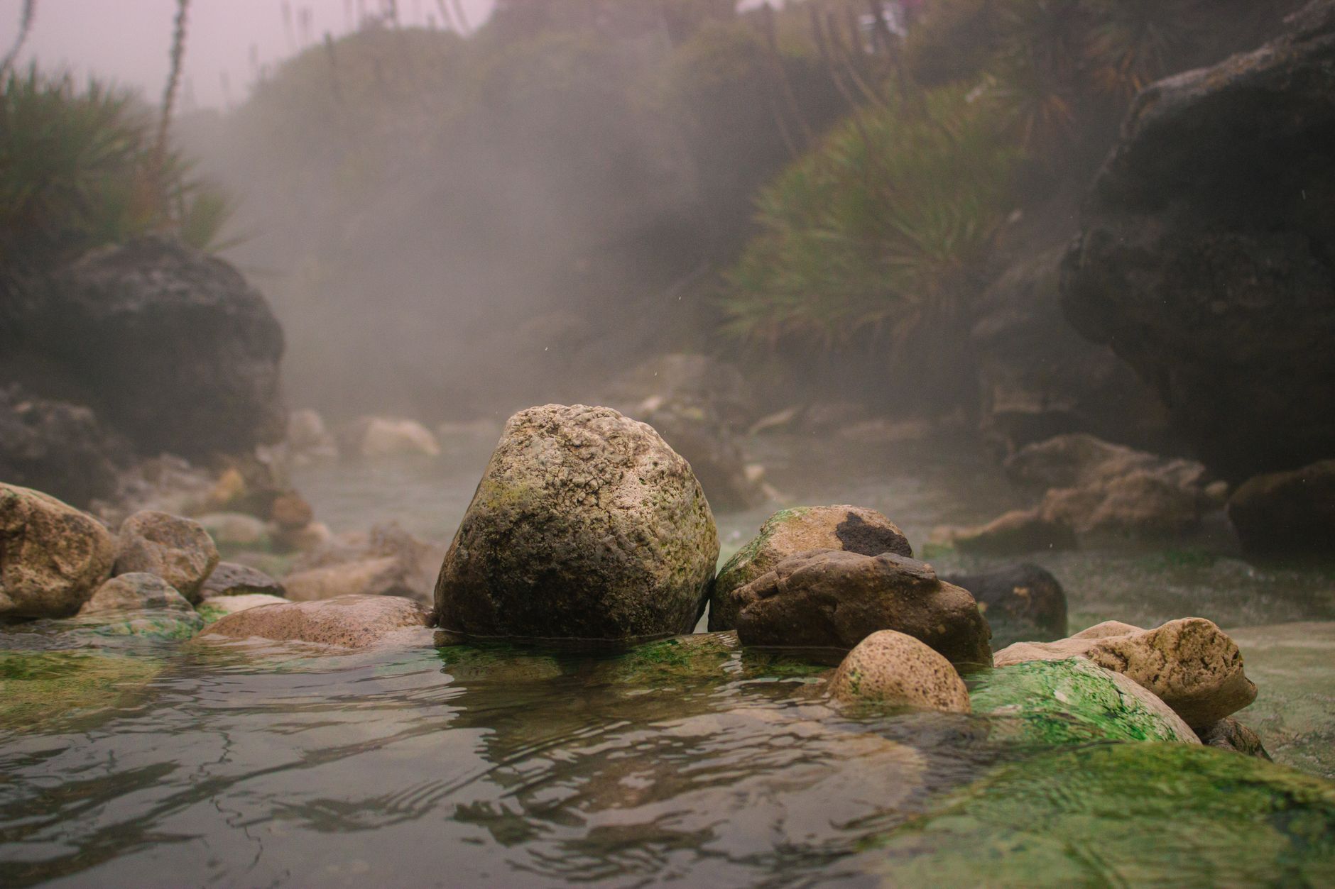 Serene foggy river with rocks, located in Manizales, Colombia, depicting a tranquil nature scene.