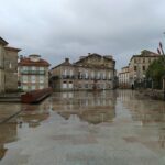 Wet square reflecting vintage buildings on a rainy day. Empty urban scene with historic charm.