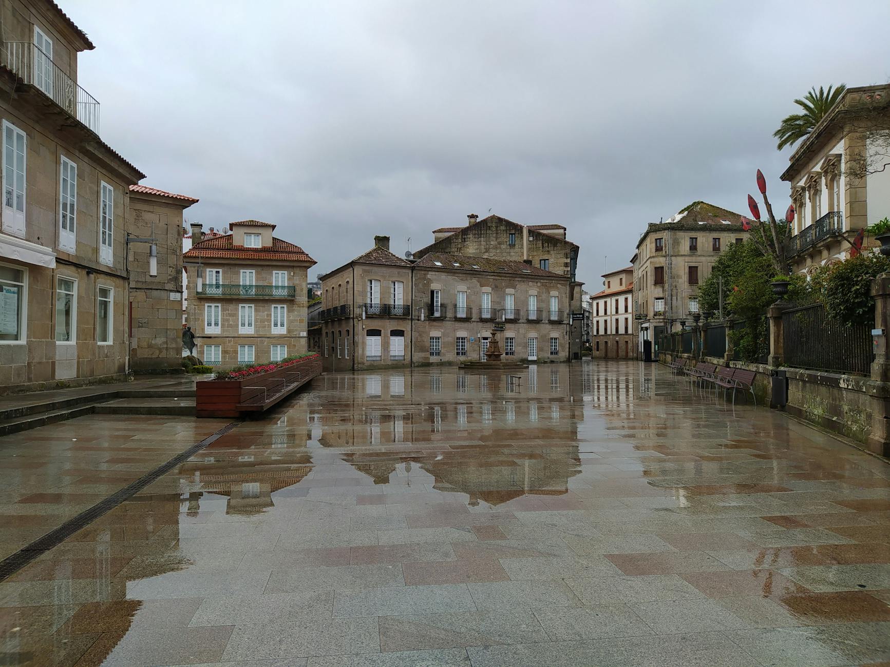 Wet square reflecting vintage buildings on a rainy day. Empty urban scene with historic charm.