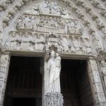 Detailed view of the ornate Gothic facade at the Notre-Dame Cathedral in Paris, showcasing intricate sculptures.