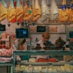 A bustling market stall in Valencia, Spain, showcasing jamón and various cheeses.