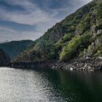 A tranquil nature scene of a river canyon surrounded by lush cliffs in Ourense, Spain.