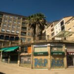 Street view of residential buildings with palm trees in Ourense, Spain, showcasing urban architecture.