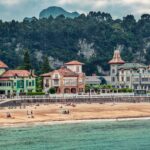 Charming beachfront view with historic buildings and scenic hills in Spain.