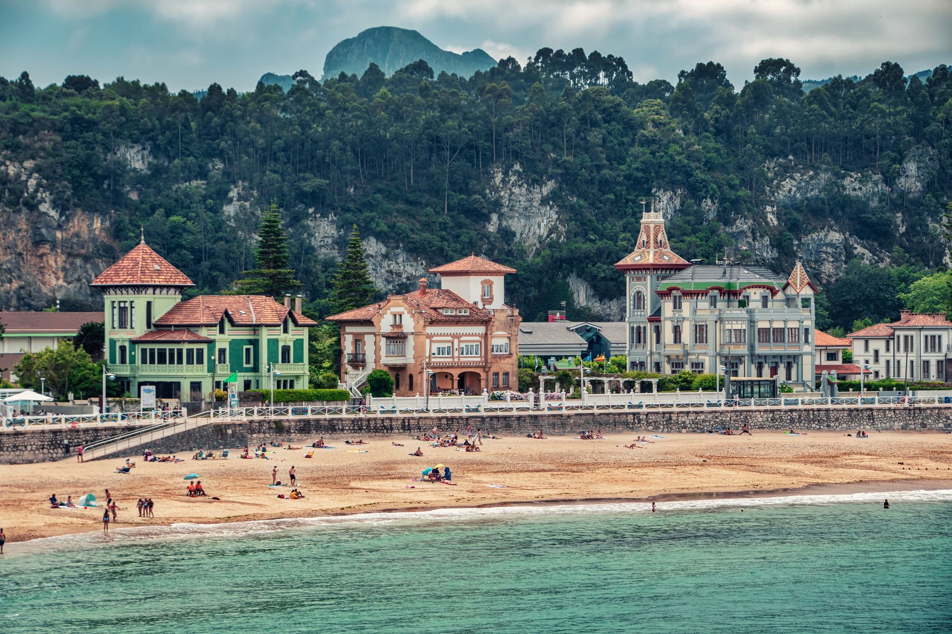 Charming beachfront view with historic buildings and scenic hills in Spain.
