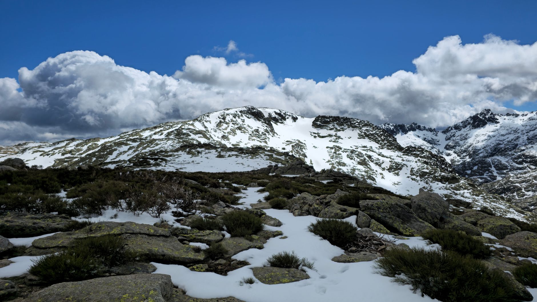 Stunning view of snow-covered peaks and dramatic clouds in Castilla y León, Spain.