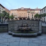 Charming old European square with a central fountain and historic buildings.