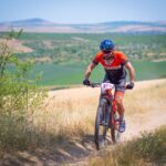 A cyclist in vibrant sportswear racing on a mountain trail in rural Tulcea, Romania.