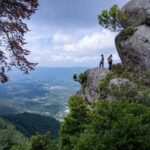 Adventurous rock climbers explore a panoramic cliffside view in El Salvador's lush mountains.