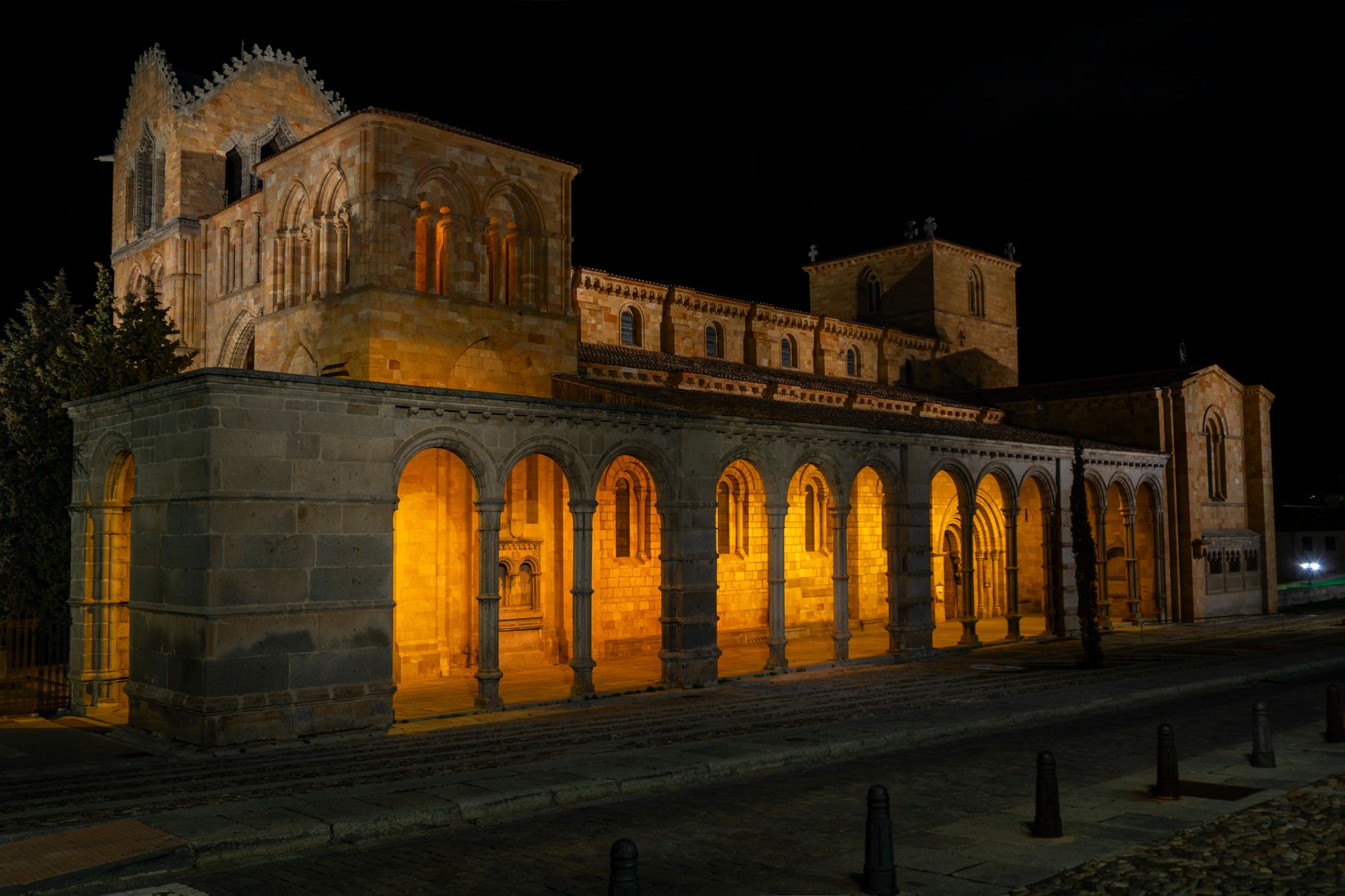 San Vicente Basilica illuminated at night in Ávila, Spain showcasing Romanesque architecture.