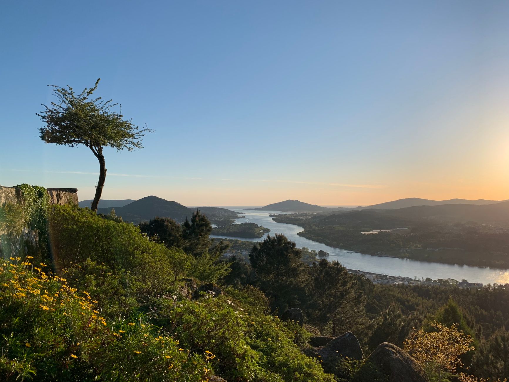 Idyllic sunset view over the Minho River with lush greenery and rolling hills.