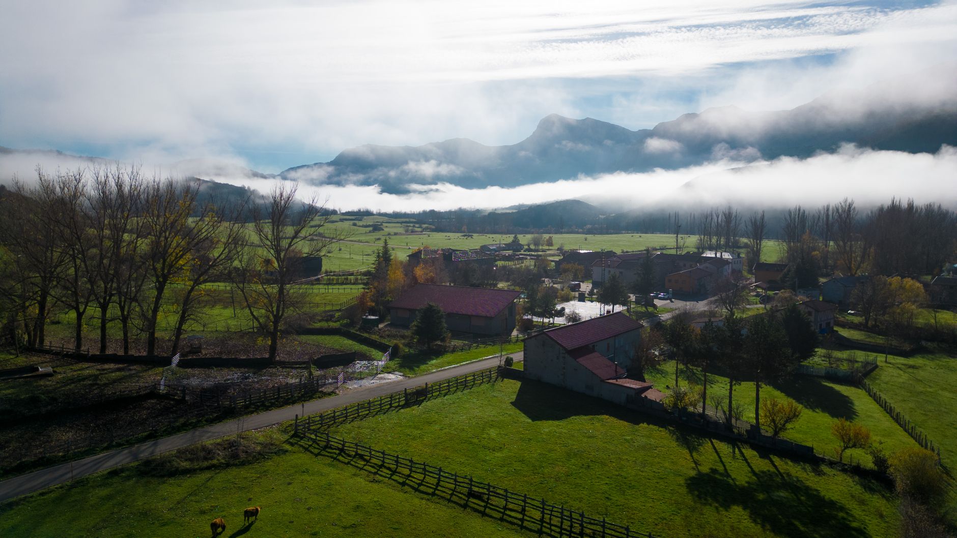 Scenic view of a misty rural landscape in Riaño, Spain with mountains and farms.