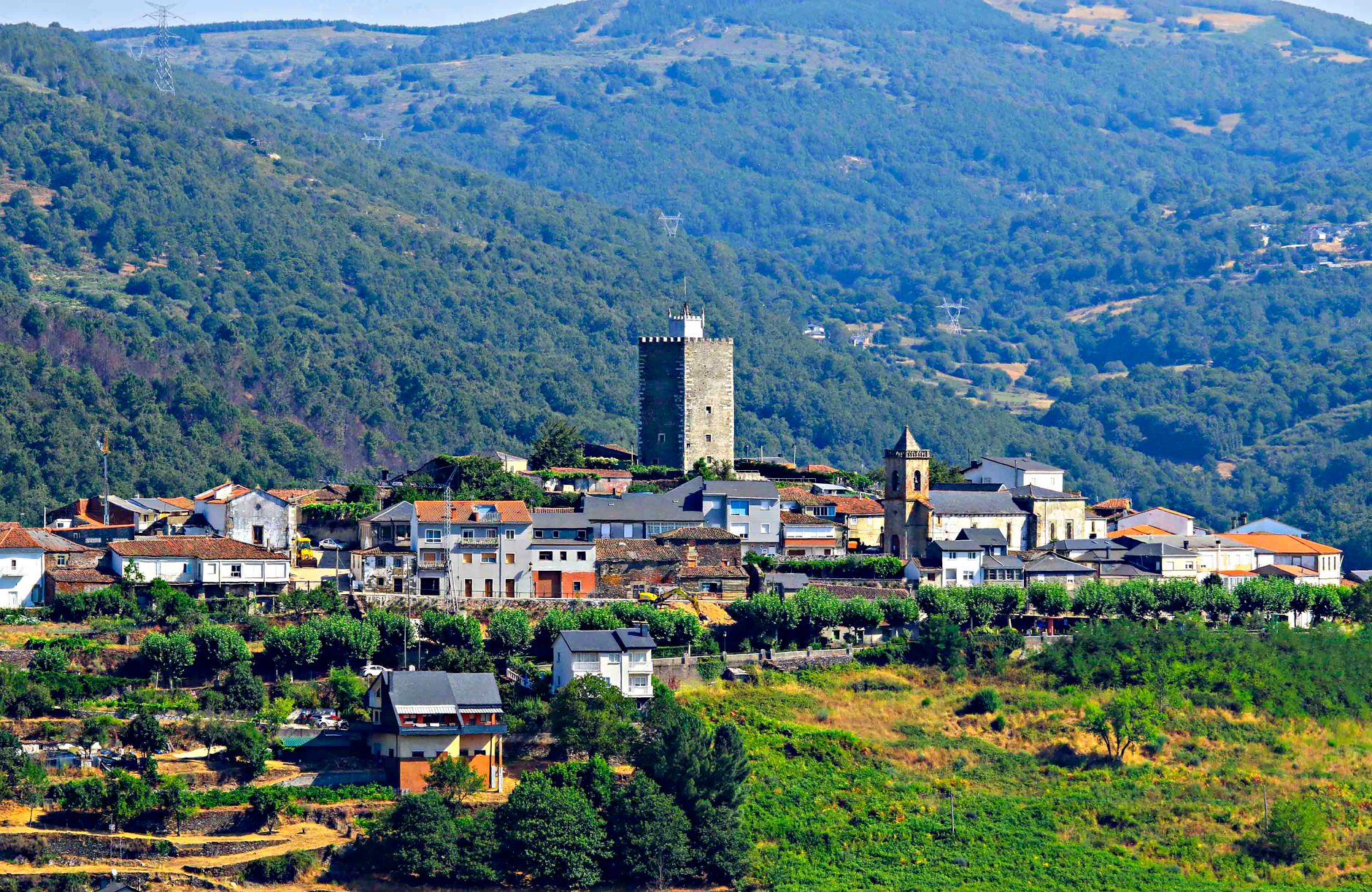 Picturesque landscape of Viana do Bolo village with historic tower and lush mountains.