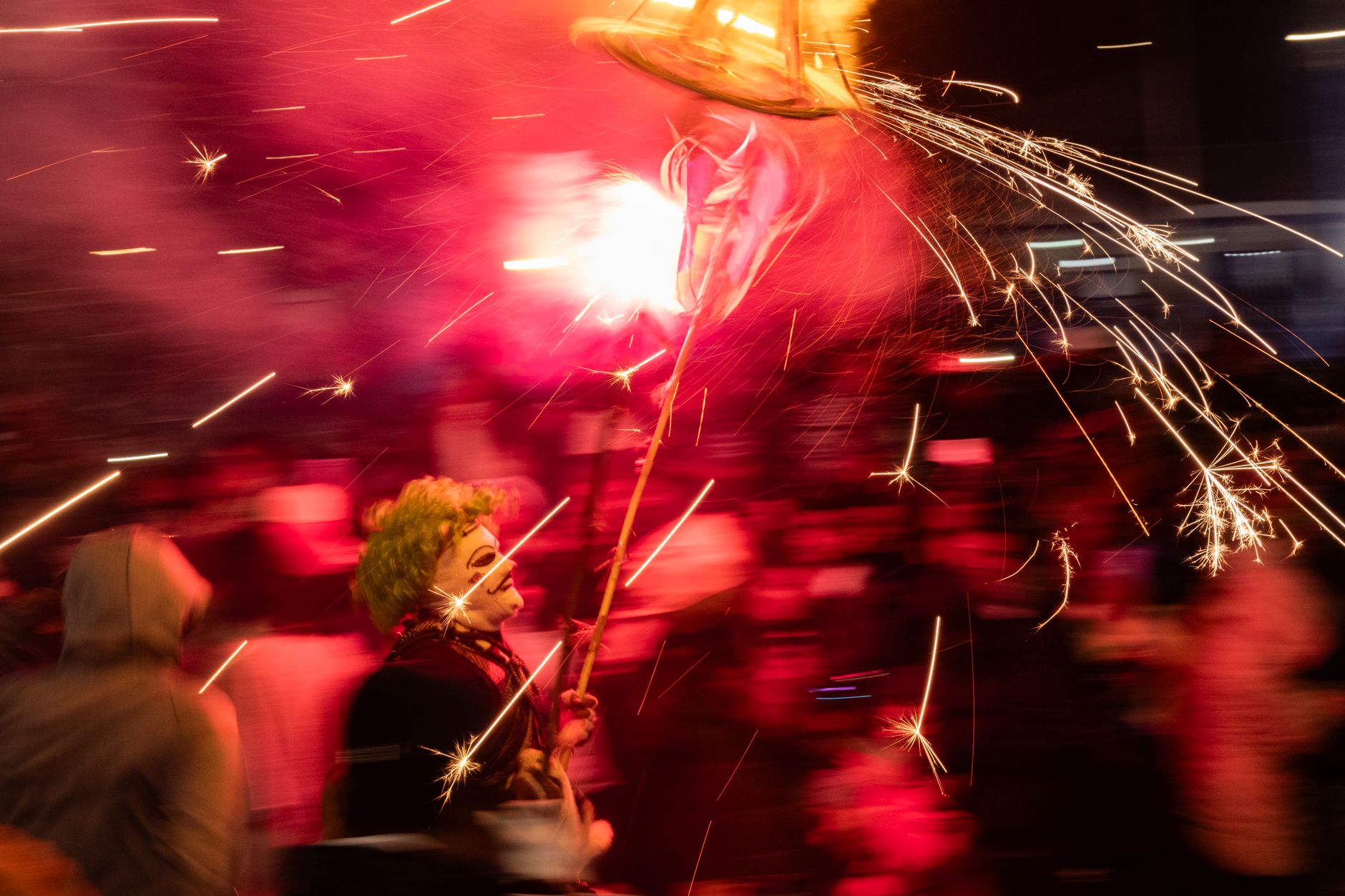 Colorful festival scene with costumed performer holding a sparkling firework, celebrating with motion blur.