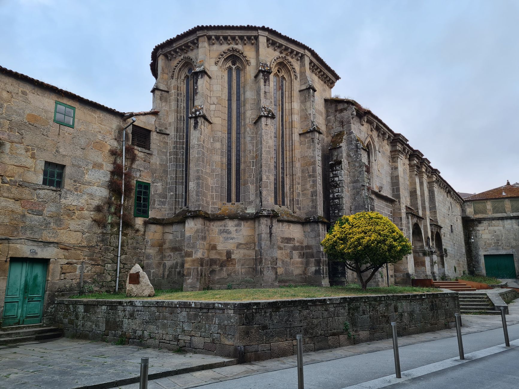 Stone Gothic church exterior with unique architecture and yellow tree.