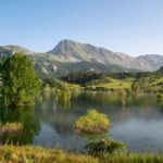 Tranquil mountain lake scene in Burón, Castilla y León, España, showcasing lush greenery and clear skies.