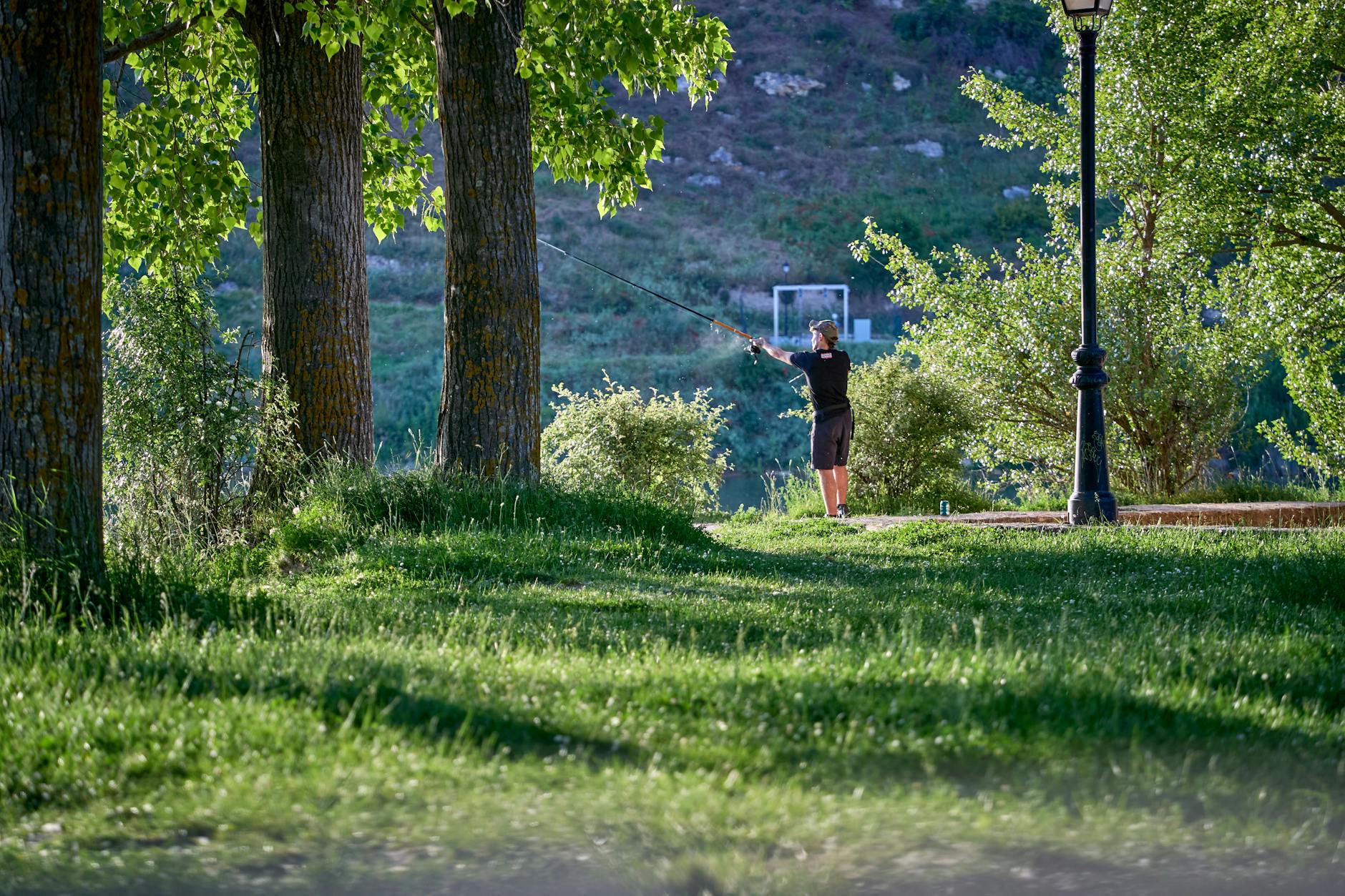 A person fishing in the serene green landscape of Maderuelo, Spain.