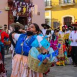 Colorful street parade in Oaxaca with traditional costumes and festive atmosphere.