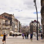Street view of Vigo, Spain showcasing urban architecture and pedestrians in a lively square.