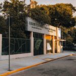 Sunlit entrance of Parque das Dunas in Natal, RN, showcasing greenery and architectural design.