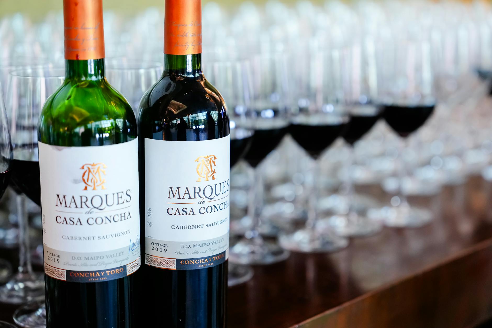 Close-up of Marques de Casa Concha wine bottles with filled wineglasses in a table setting.