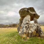 Explore a Neolithic dolmen under a moody sky in the picturesque Basque countryside.