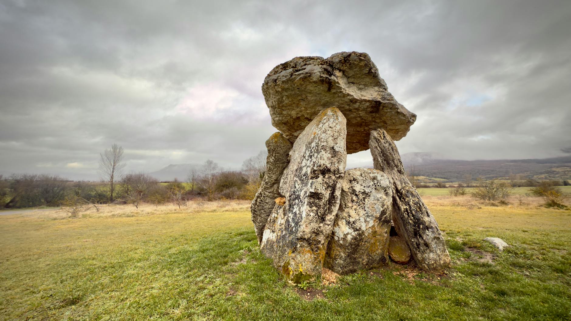 Explore a Neolithic dolmen under a moody sky in the picturesque Basque countryside.