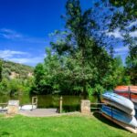 Colorful kayaks stacked by the Duero River in Soria, Spain on a sunny day, perfect for outdoor adventures.