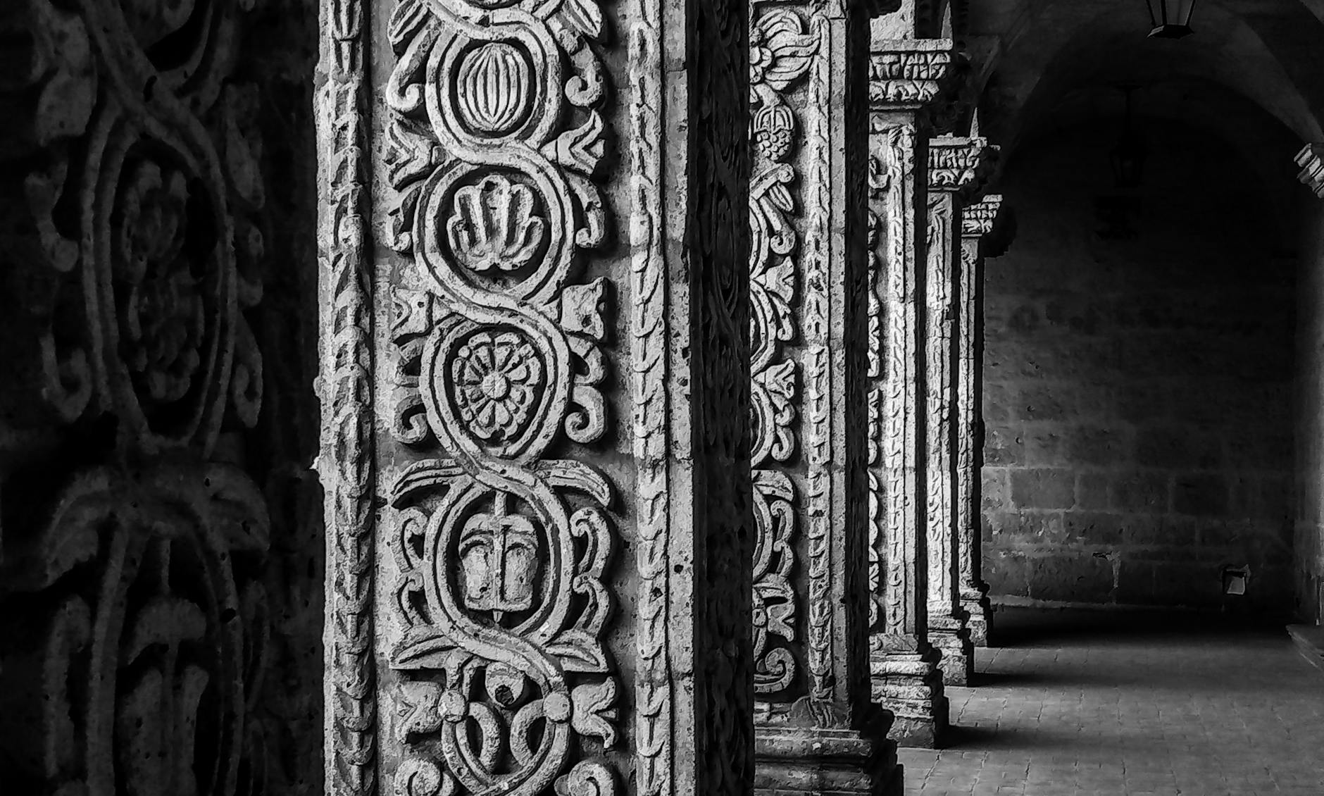Intricate stone columns at an ancient Arequipa monastery, showcasing detailed carvings in black and white photography.