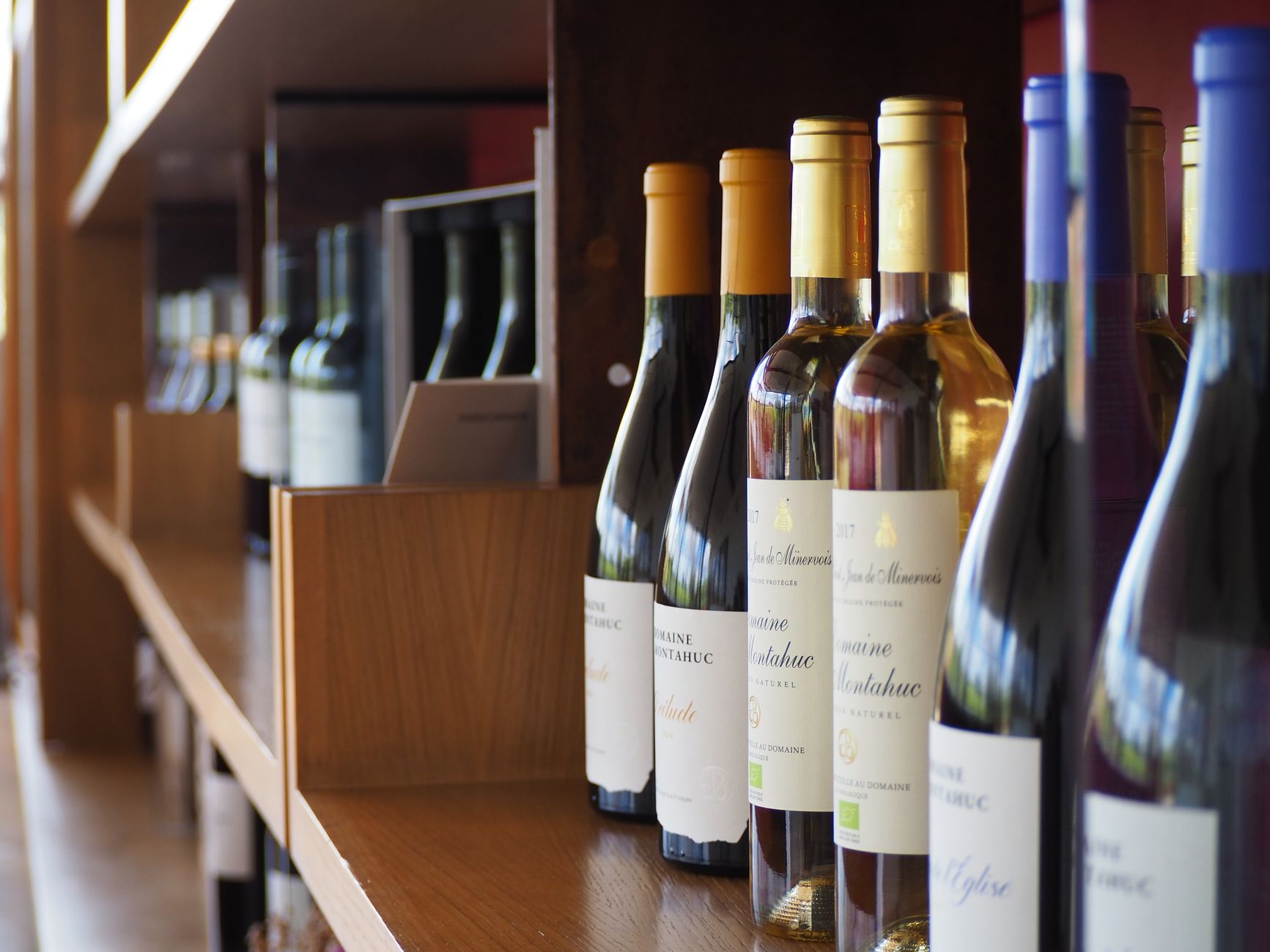 Close-up of wine bottles on a wooden shelf in a Valencia winery.