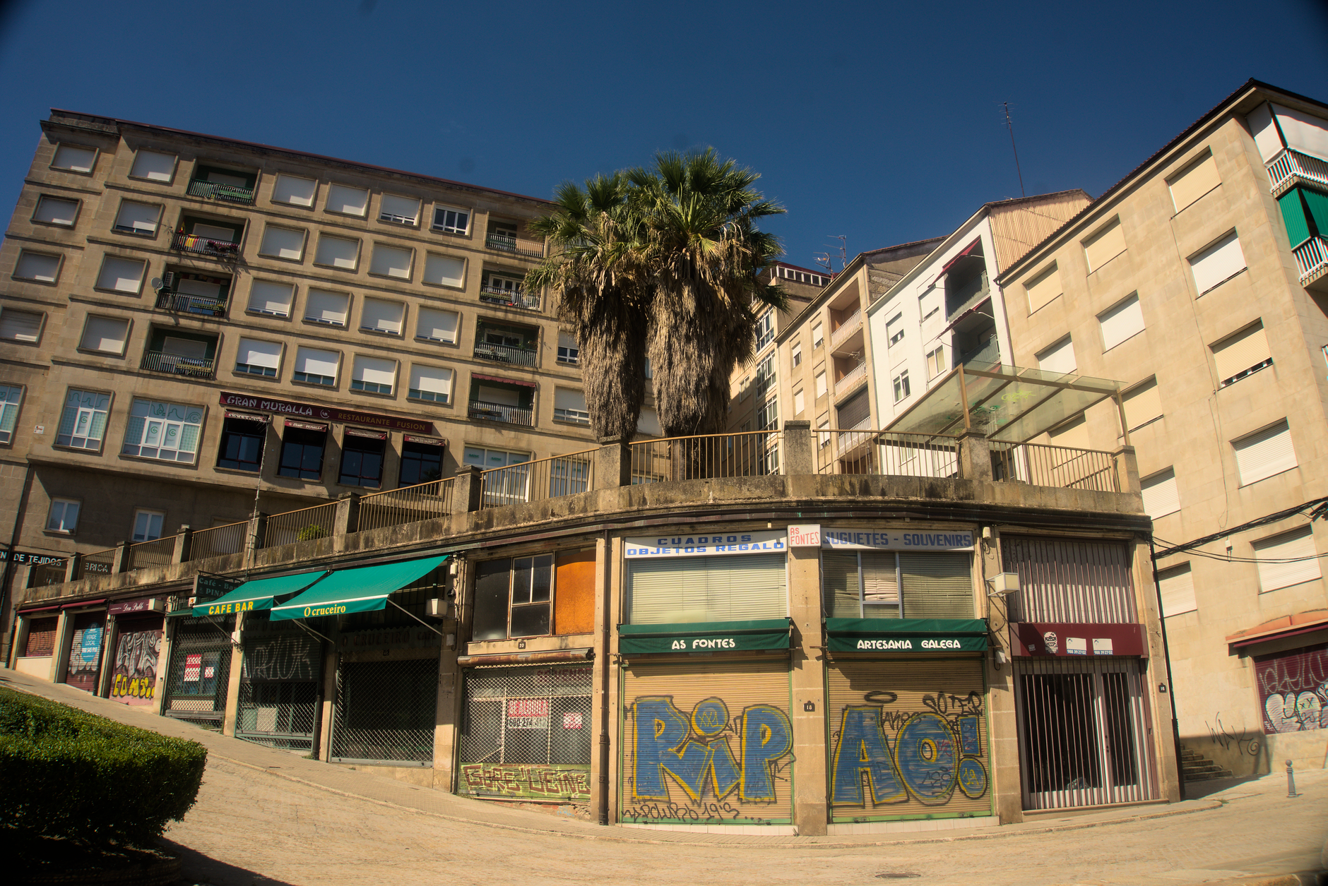 Street view of residential buildings with palm trees in Ourense, Spain, showcasing urban architecture.