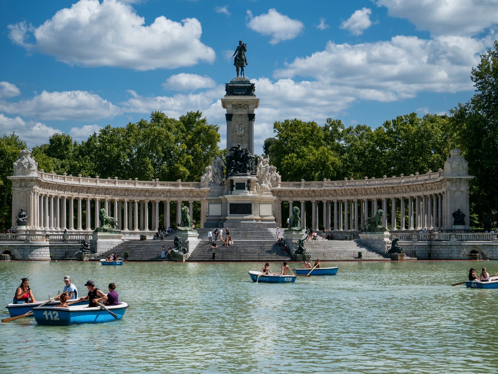 People enjoy boating at the iconic Retiro Park with Alfonso XII Monument, Madrid.