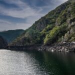 A tranquil nature scene of a river canyon surrounded by lush cliffs in Ourense, Spain.