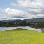 Idyllic landscape view of a river flowing through Ponte de Lima, Portugal, with lush greenery and mountains.