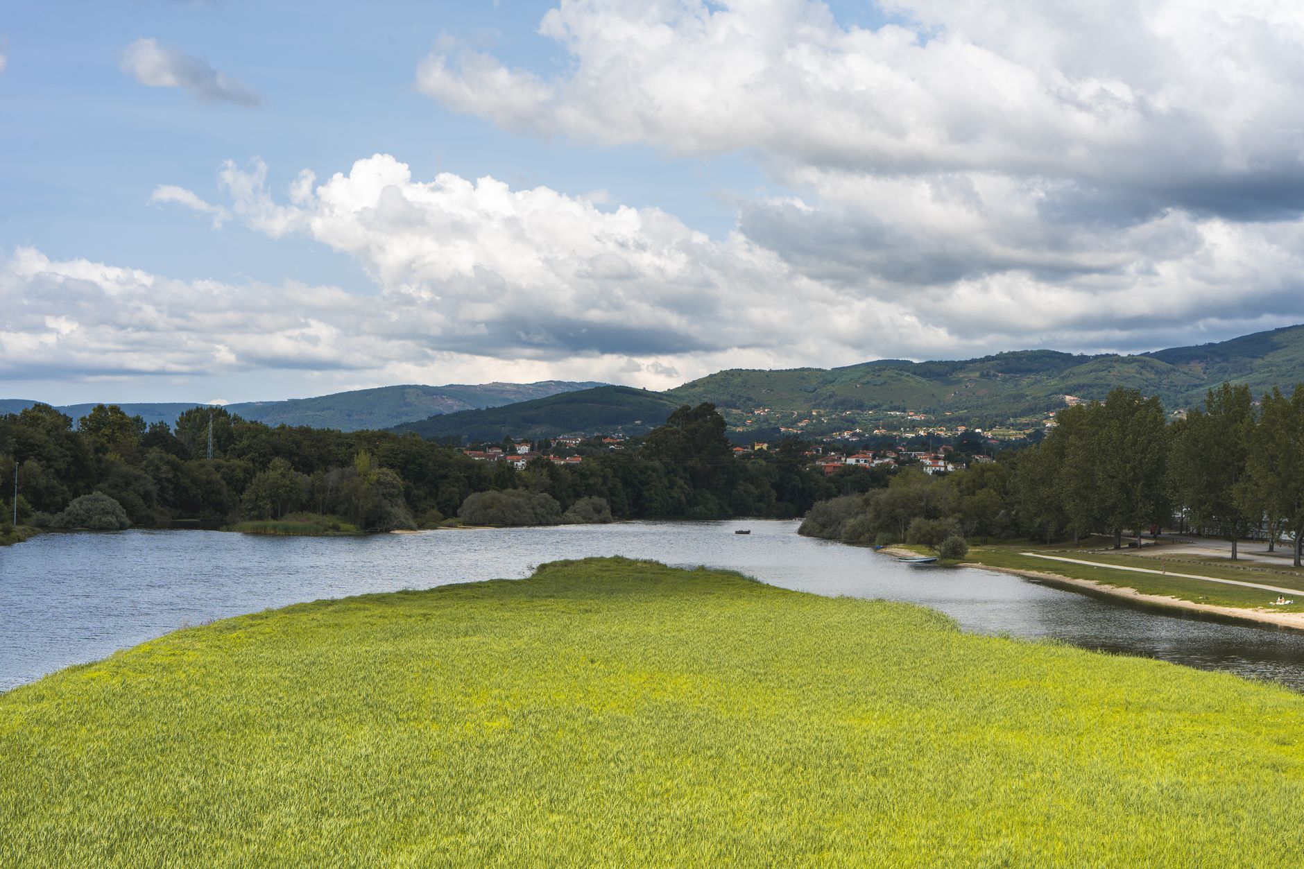 Idyllic landscape view of a river flowing through Ponte de Lima, Portugal, with lush greenery and mountains.