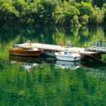 Peaceful scene of boats on a pier surrounded by lush greenery in Sober, Galicia.