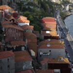 Picturesque coastal town with red roofs, waterfront road, and serene sea view.