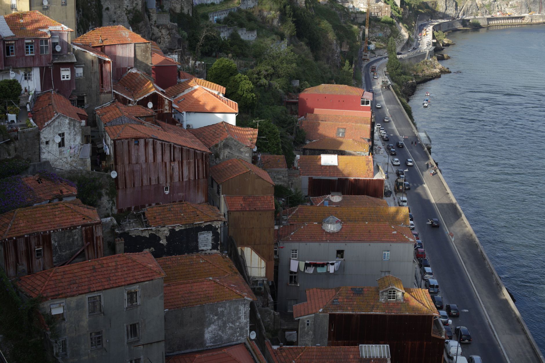 Picturesque coastal town with red roofs, waterfront road, and serene sea view.