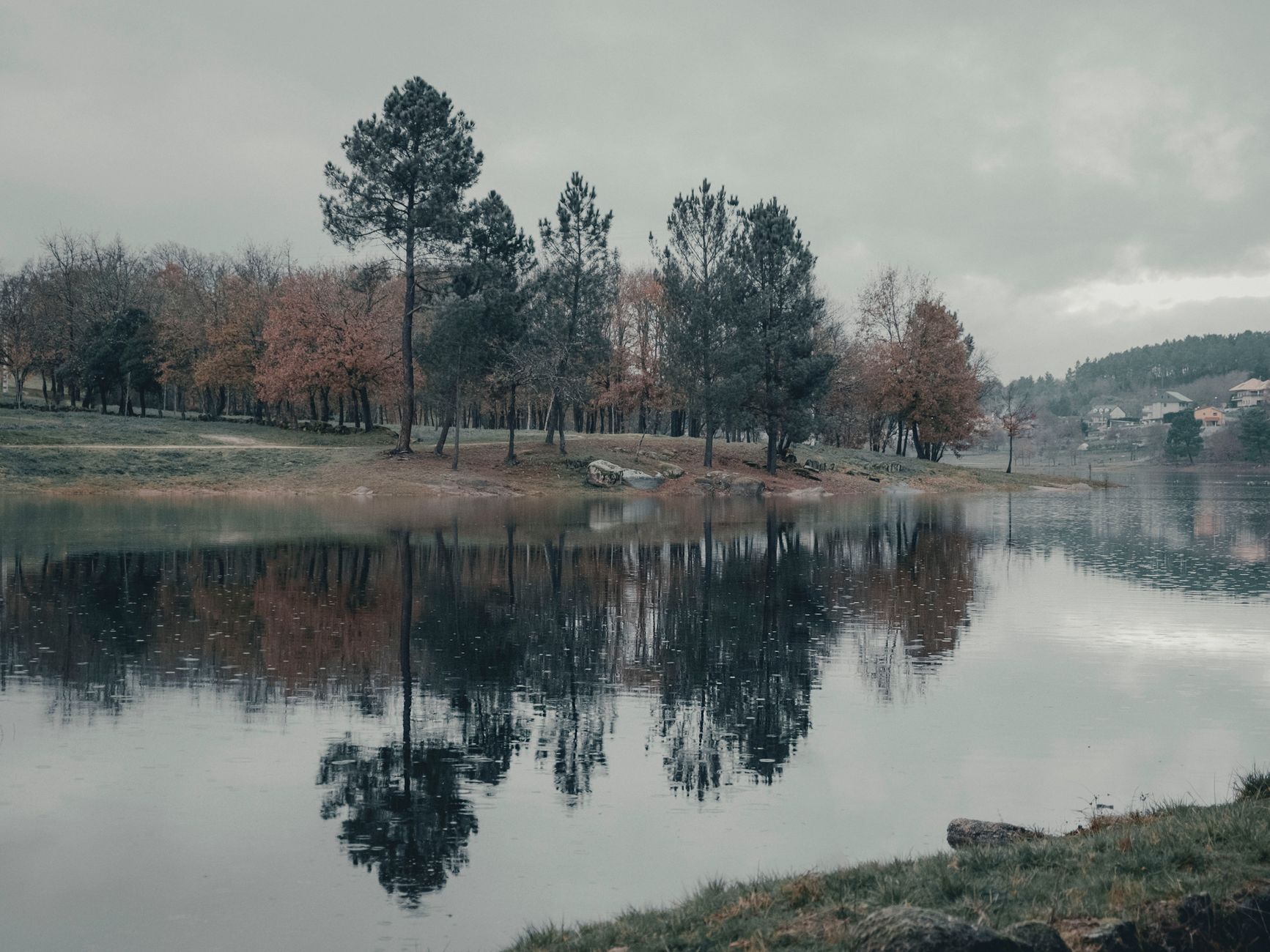 Tranquil autumn landscape with trees reflected in a lake at Cachamuíña, Galicia, Spain.