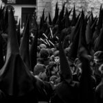 Black and white image of a religious procession in Jaén, Spain featuring capirotes and traditional garments.