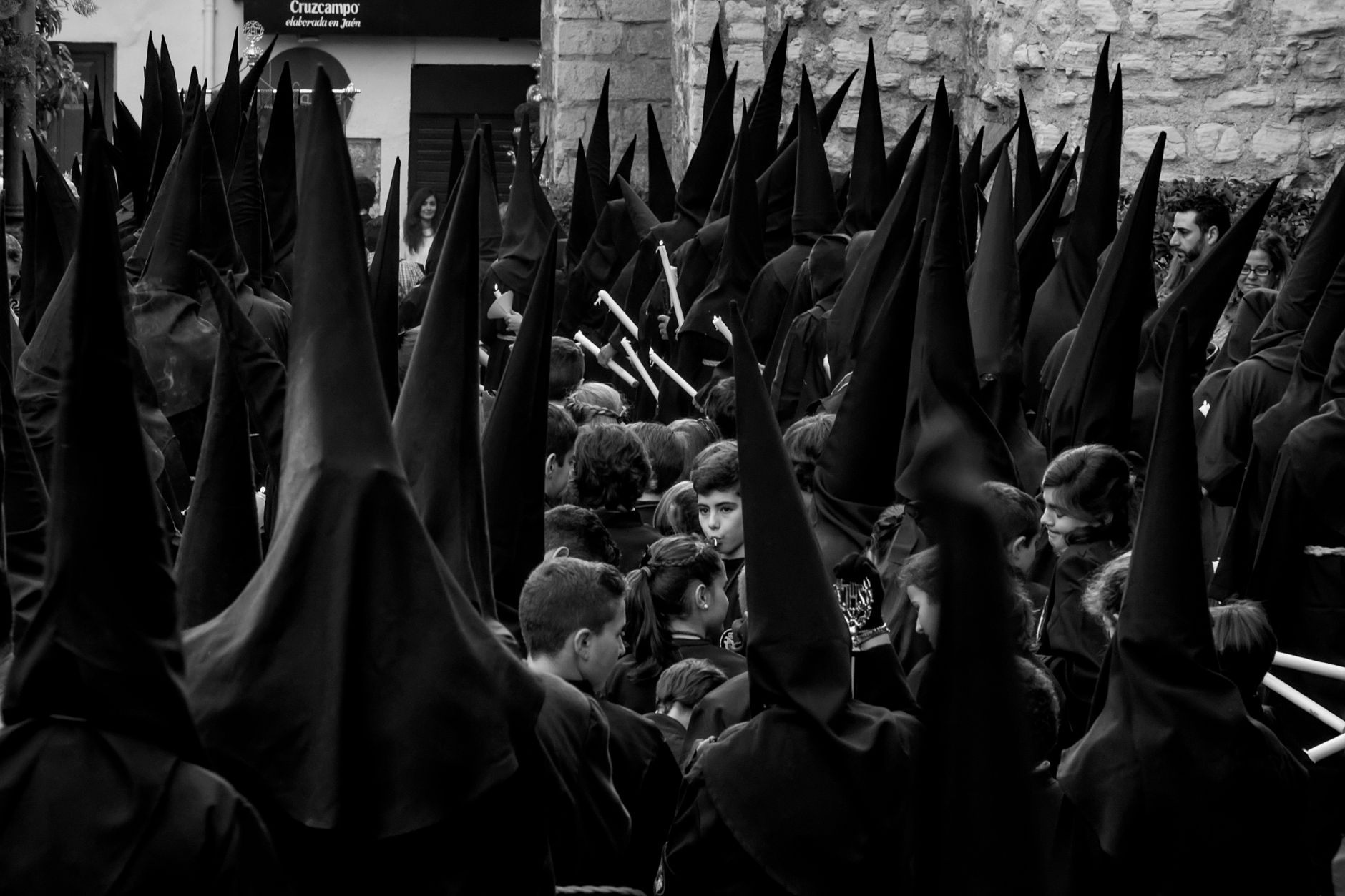 Black and white image of a religious procession in Jaén, Spain featuring capirotes and traditional garments.